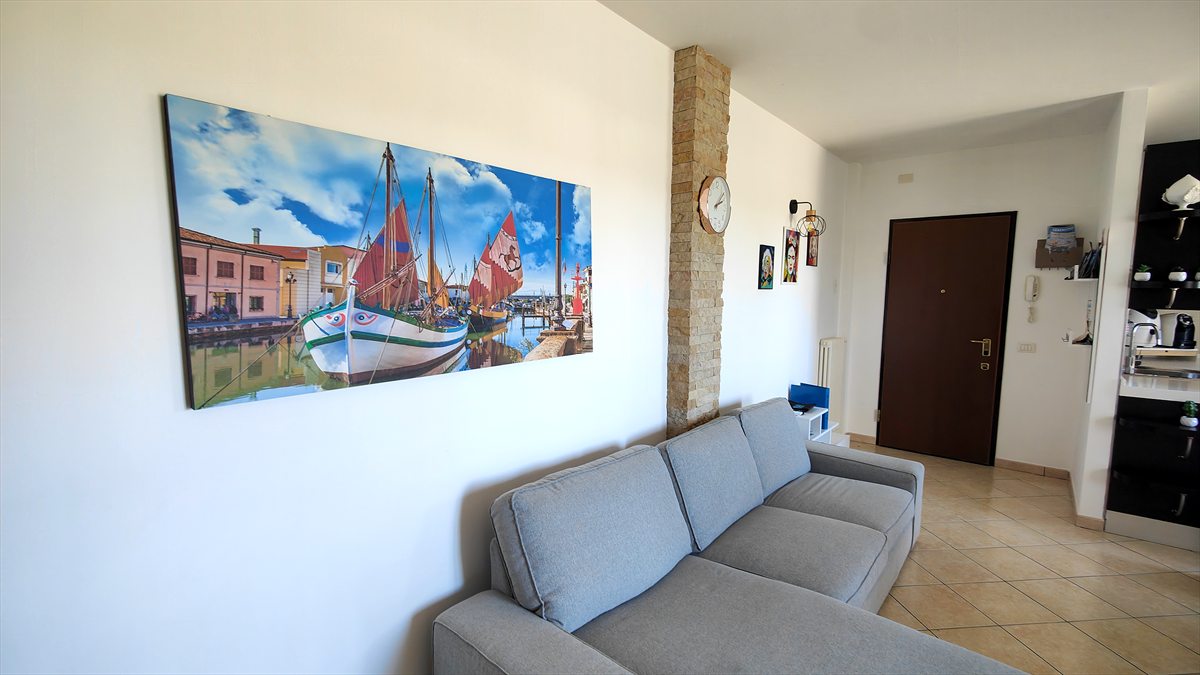 Il soggiorno con il divano e il quadro del porto canale di Cesenatico